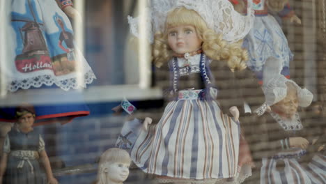 Rag-Doll-Toy-Baby-with-Iconic-Dutch-Clothes,-Rotating-on-Turntable,-Showcasing-at-Shop-Display-Window-of-City-Store-in-slowmo