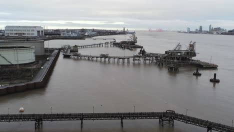 Drone-view-Tranmere-oil-terminal-Birkenhead-coastal-petrochemical-harbour-distribution-rising-forward-to-pontoon-cranes