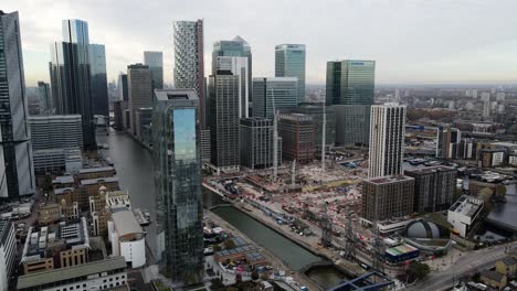 Aerial-pan-shot-showing-Canary-Wharf-luxury-skyscraper-buildings-with-river-Thames-in-London,UK