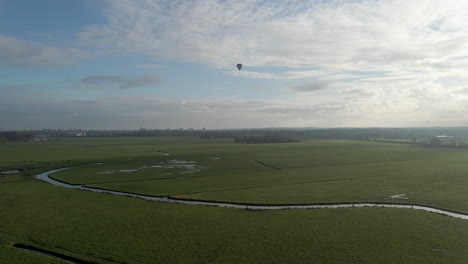 Aerial-jib-up-of-beautiful-dutch-landscape-with-a-hot-air-balloon-in-the-distance