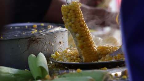 Threshing-boiled-yellow-maize-corn-with-knife,-hot-boiled-maize-corn