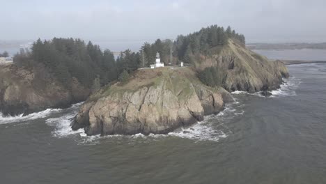 Cape-Disappointment-Lighthouse-sits-high-above-the-churning-pacific-ocean-waves,-aerial-orbit