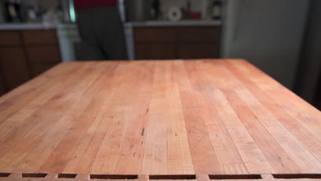 Close-Up-Of-A-Wooden-Butcher-Block-In-The-Kitchen-With-Person-Standing-In-Defocused-Background,-static-shot