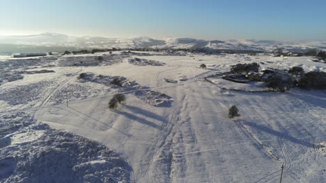 Schneebedeckte-Ländliche-Winterlandschaft-Spur-Fußabdruck-Schatten-Terrain-Luftaufnahme-Langsam-Nach-Links-Schwenken