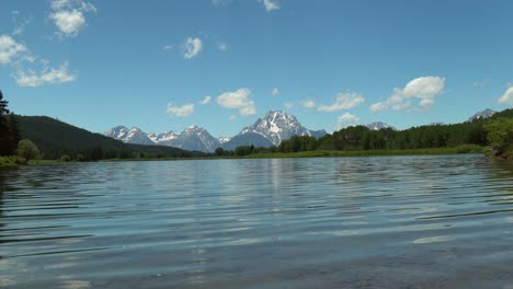 View-from-Snake-River-of-the-Tetons-reflecting-in-the-rippling-water-in-summer-in-Grand-Teton-National-Park