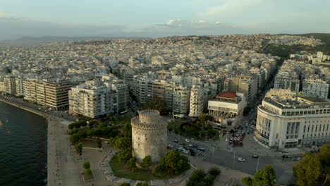 Filmikone,-Historisches-Wahrzeichen-Des-Weißen-Turms-Von-Thessaloniki-Drohne,-Luftaufnahme-Der-Stadt-Bei-Sonnenuntergang-In-4k