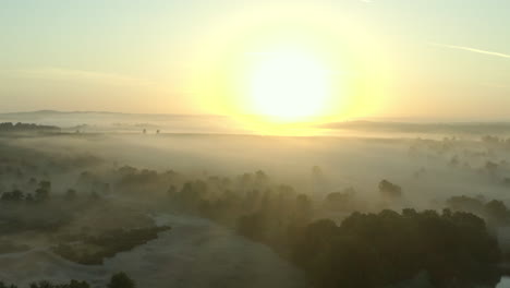A-misty,-foggy-sunrise-in-the-beautiful-English-countryside,-with-trees-and-a-lake-in-the-foreground