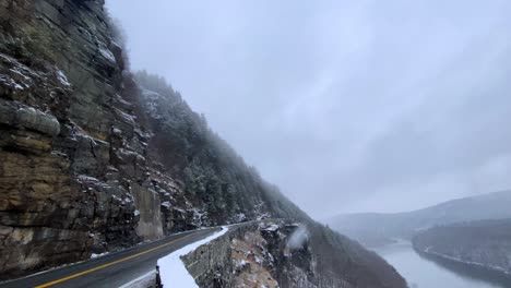 River-valley-Highway-with-cliffs-and-hills-and-clouds-on-a-snowy-winter's-day-with-snowfall-and-a-river-below