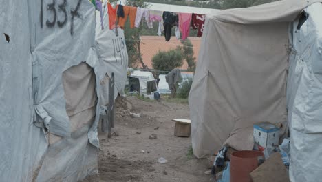 A-man-living-in-Moria-Refugee-camp-jungle-overspill-carries-pallet-between-makeshift-shelters,-inhuman-living-conditions