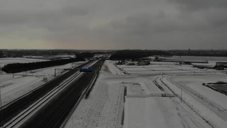 A-Car-Passing-By-The-Highway-Next-to-The-Snowy-Field