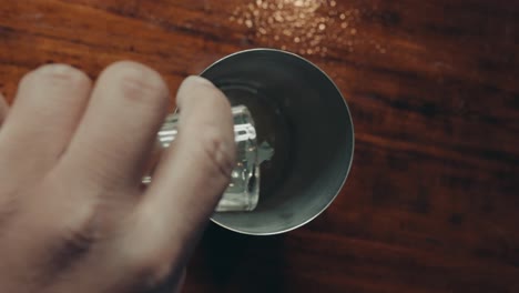 Top-down-view-of-bartender's-hand-adding-lime-juice-into-metal-cocktail-shaker,-full-frame