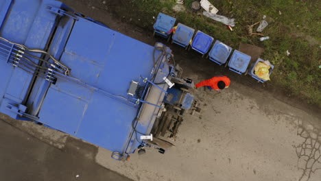 Aerial-top-down-shot-of-Garbage-collectors-getting-trash-bins-working-and-collecting-trash-into-truck
