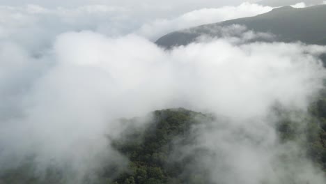 Flying-above-the-clouds-over-a-green-mountain