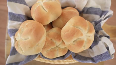 Freshly-Baked-Kaiser-Rolls-in-Woven-Basket-on-Wooden-Background,-Top-Down-View