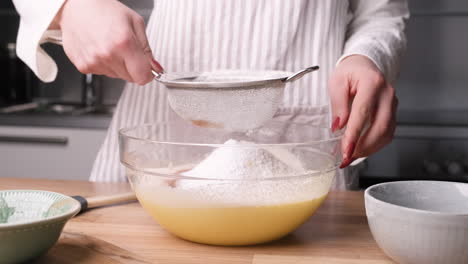 Woman-Sifting-Flour-Through-Sieve-Into-A-Glass-Bowl-With-Mixture