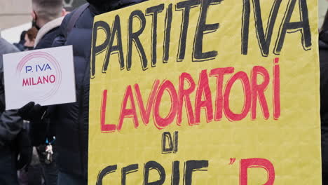 Ein-Mann-Hält-Während-Einer-Demonstration-Auf-Dem-Platz-In-Mailand,-Italien,-Eine-Gelbe-Protestplakatwand-Gegen-Die-Italienische-Regierung
