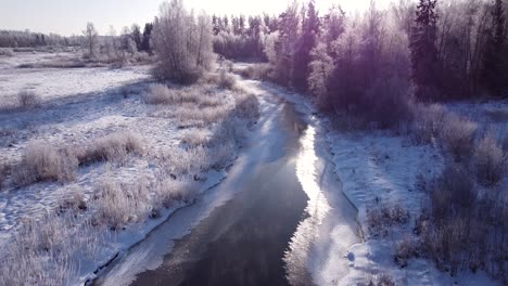 Winter-partially-frozen-river-in-forest-landscape-aerial-view