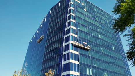 An-office-building-gets-window-cleaning-from-workers-on-a-high-swing-stage-suspended-scaffold