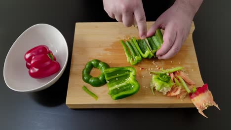 Slicing-a-green-bell-pepper-on-a-cutting-board,-medium-shot-overhead