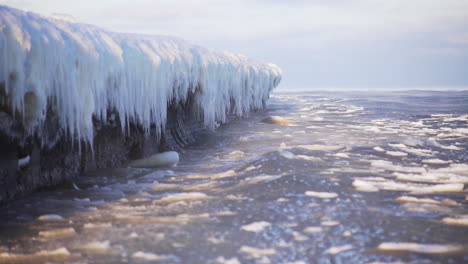 Cold-sea-waves-crashing-against-icy-coastline,-arctic-icicles,-global-warming