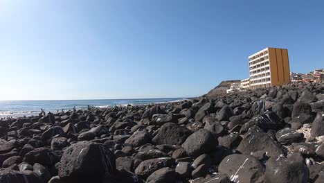 Pan-from-a-resort-hotel-at-Rocky-Point,-Mexico-to-the-coastline-covered-with-volcanic-rock-and-pelicans