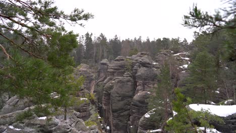 outlook-on-a-sandstone-rock-formation-through-branches-in-Prachov-Rocks,-Bohemian-Paradise,-in-winter,-dolly-in