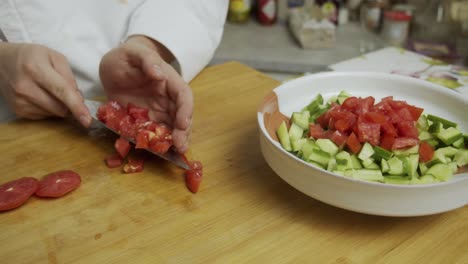 Chef-cuts-tomatoes-and-puts-slices-into-the-plate-with-vegetable-salad