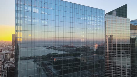 Aerial-pan-right-of-Puerto-Madero-docks-mirrored-in-window-glass-skyscrapers-at-sunset,-Buenos-Aires