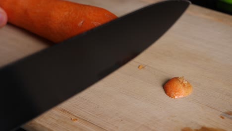 Cutting-of-the-front-and-back-of-a-carrot-in-slow-motion-on-a-chopping-board