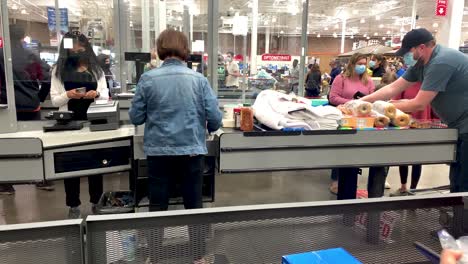 Costco-essential-employee-or-cashier-or-worker-female-wearing-face-mask-scanning-the-grocery-items-of-the-customer