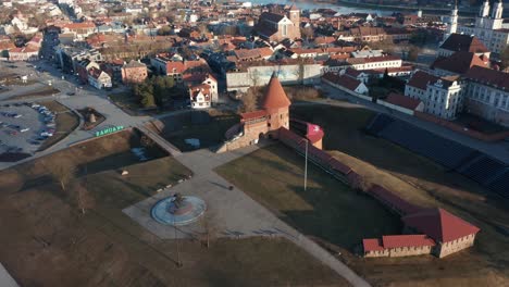 AERIAL:-Reveal-Shot-of-Kaunas-Castle-and-Oldtown-in-Golden-Hour-Evening-Light