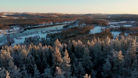 Beautiful-aerial-view-of-a-small-village-in-Lappland,-Sweden-surrounded-by-high-pine-forest-at-sunset--Slow-tracking,-drone-shot