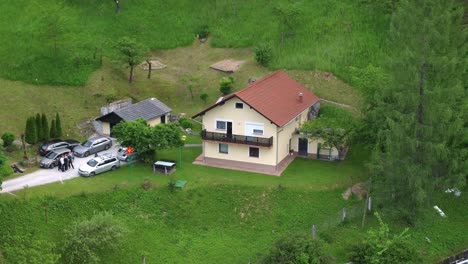 Aerial-view-of-family-house-with-parked-cars-between-green-idyllic-nature