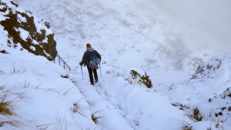 Solo-backpacker-woman,-with-trekking-gear,-trekking-the-snowy-covered-mountainous-terrain