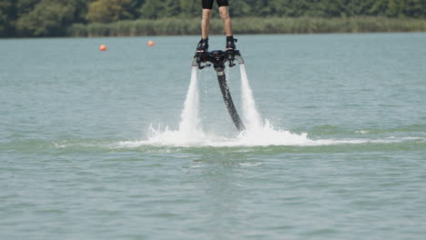 Medium-slow-motion-shot-of-flyboarder-flying-over-natural-lake-in-summer