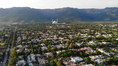 Aerial-Tilt-Up-View-Across-Islamabad-Cityscape-With-Faisal-Masjid-Reveal-At-Foothill-Of-Margalla-Hills