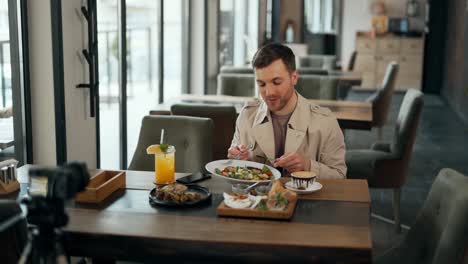Charismatic-adult-male-blogger-talks-about-food-on-camera-in-a-restaurant