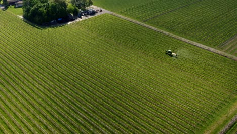 Aerial-circling-of-farming-tractor-spraying-herbicides-and-pesticides-on-vineyard