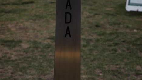 Metallic-marker-at-border-between-Canada-and-United-States-tight-shot-slow-pan-up