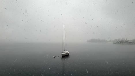 Beautiful-unique-shot-of-snow-falling-over-Maggiore-lake-and-moored-boat,-Italy