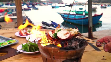 Grilling-lobster-outdoors-on-clay-charcoal-stove-in-quiet-fishing-port,-Vietnam