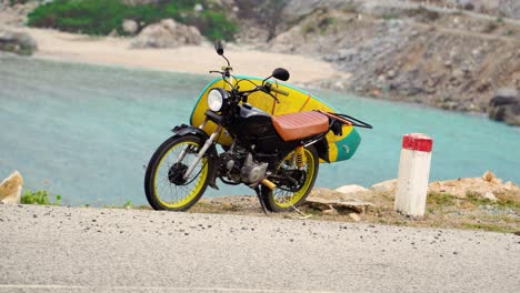Motorbike-With-Yellow-Surfboard-Attached-Standing-On-Kickstand-Beside-Sea-View