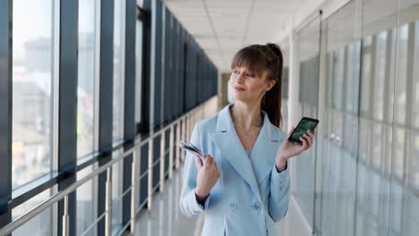 Medium-plan-of-young-attractive-girl-in-business-suit-showing-smartphone-and-bundle-of-money