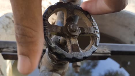 A-man's-hand-opens-a-valve-on-a-water-pipe