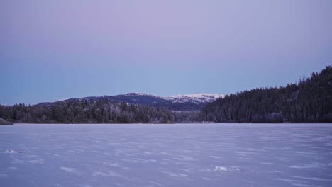 Frosted-Lake-With-Dense-Spruce-Woodland-And-Snowcapped-Mountains-Near-Trondheim,-Norway