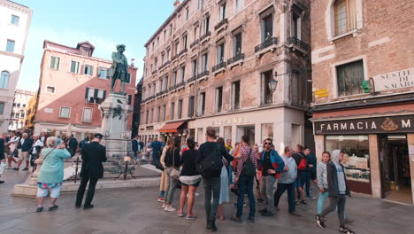 Slow-motion-pan-shot-of-tourists-taking-pictures-of-italian-statue-of-Daniele-Manin-in-the-centrum-of-Venice,-Italy