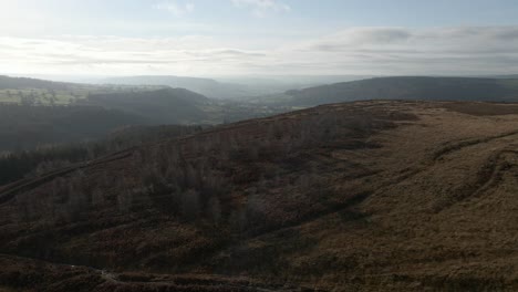 A-long-4k-drone-shot-flying-over-moorland-looking-down-a-green-valley-in-Autumn