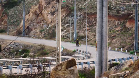 Man-rides-on-motorbike-transporting-surfboard-on-empty-Vietnam-countryside-road