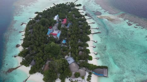 Tropical-island-in-Maldives-with-piers-and-docks-close-to-white-sandy-beach,-resorts-and-restaurants-in-palm-trees-forest