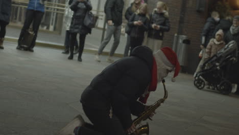Street-musician-dressed-like-Santa-Claus-play-on-saxophone